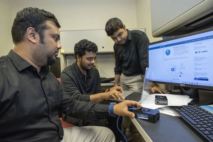 Members of Dr. Khalil's research team discussing the AI reliability project in the TITANS Laboratory.