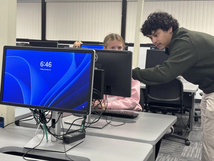 Student helping someone at computer