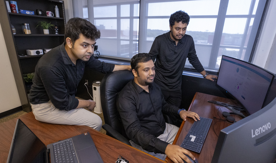 Dr. Alvi Ataur Khalil and members of his research team reviewing the AI reliability evaluation platform at a computer workstation.